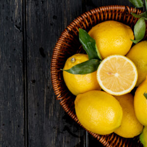 top view of fresh ripe lemons in a wicker basket on black background with copy space