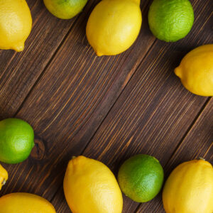 Scattered lemons with limes flat lay on a wooden background
