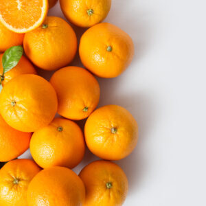 Bright juicy ripe orange fruits with leaves isolated on white background. Closeup, top view, copy space. Natural vitamin or organic food concept